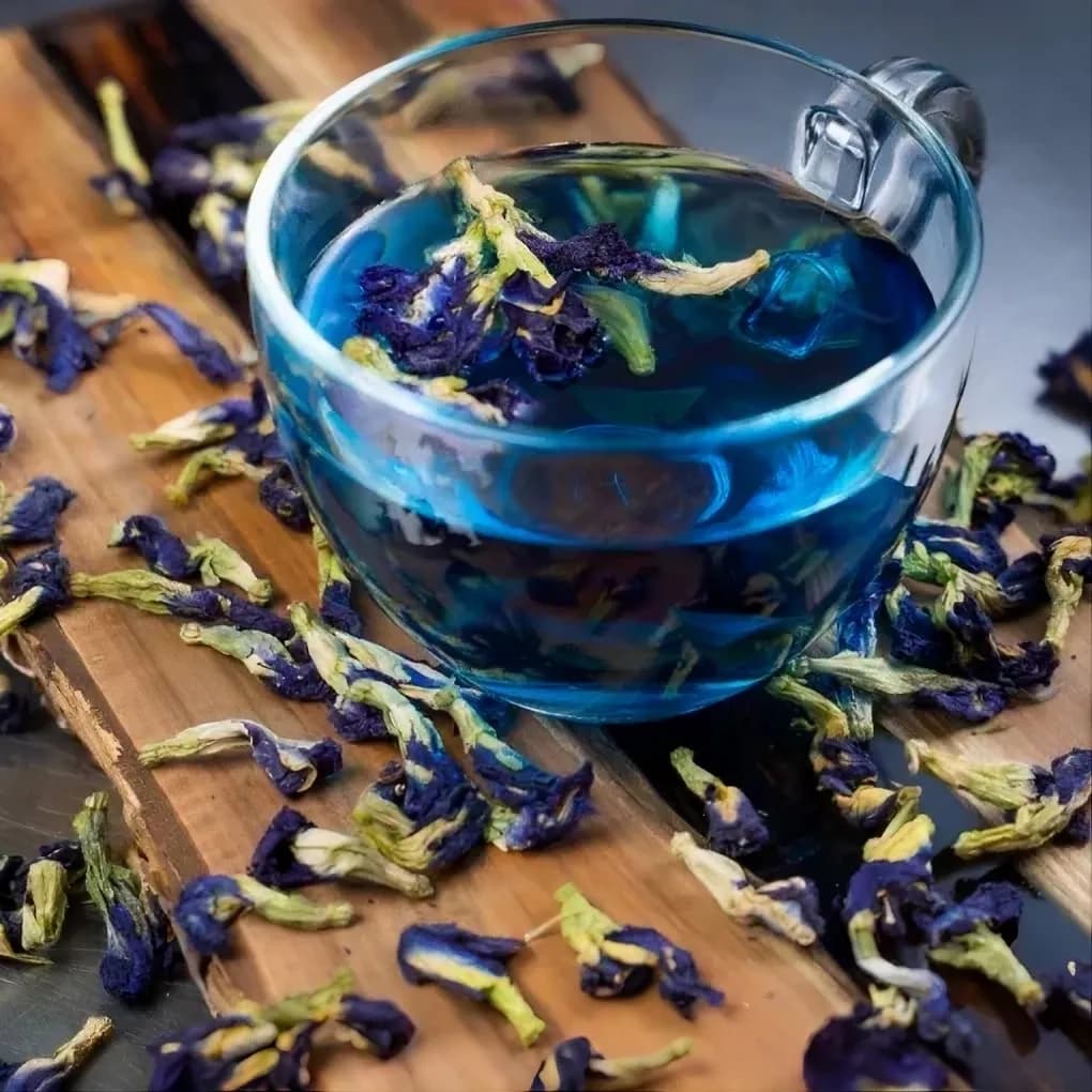 Чай синего цвета в стеклянной чашке с цветами